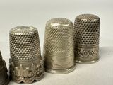 three silver thimbles sitting next to each other on a white surface