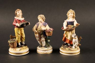 trois figurines représentant des enfants avec des paniers de fleurs et un chien