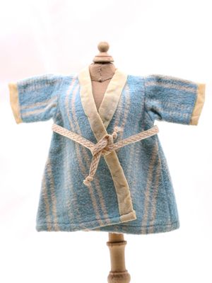 une robe bleue posée sur un mannequin en bois, sur fond blanc