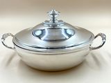 a silver casserole with a lid on a white table
