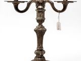 an antique silver plated candelab with three candles on a stand