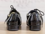 pair of black leather shoes with laces on a wooden surface
