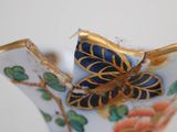 a blue and gold vase with a butterfly on it