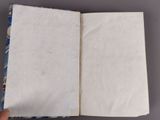 someone is holding an open book on a table with a pattern on it