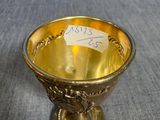 une tasse plaquée or, sur laquelle est collé un autocollant, posée sur une table