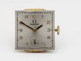a close up of a silver and gold clock on a white surface