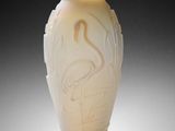 a white vase with a bird on it sitting on a table