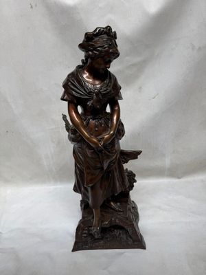 statue en bronze représentant une femme assise sur un rocher avec un chien