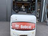 a picture of a bobcat forklift parked in front of a building