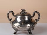 silver plated teapot with dragon handles on a white table