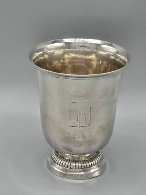 une coupe en argent posée sur un socle, sur fond gris