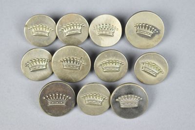 six silver buttons with crowns on them on a white surface
