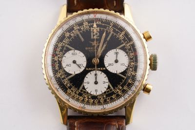 une montre en or avec un cadran noir et un bracelet en cuir marron