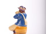 a figurine of a man sitting on a stool with a hat on his head