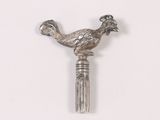 a silver bird on top of a pen on a white surface