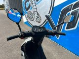 un scooter garé devant un panneau bleu et blanc