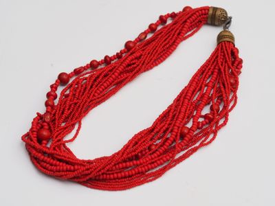 a close up of a red beaded necklace on a white surface