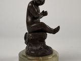 an image of a statue of a child sitting on a rock