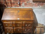 a small wooden desk with drawers and a suitcase on the floor