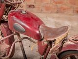an old red motorcycle parked in front of a brick wall