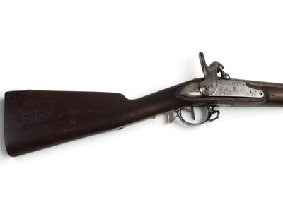 un vieux fusil exposé sur une surface blanche