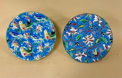 two blue plates with floral designs on them sitting on a table