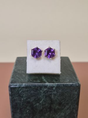 une paire de boucles d'oreilles en améthorate posées sur un bloc de marbre