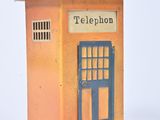 une cabine téléphonique miniature avec une porte bleue et un toit marron