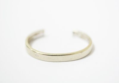 a close up of a silver cuff bracelet on a white surface