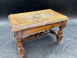 une vieille table en bois avec un plateau sculpté et des pieds tournés