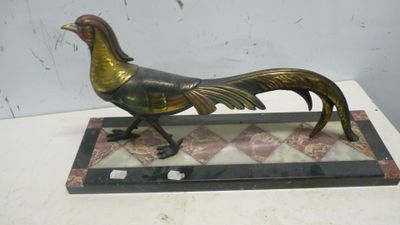 statue d'un coq doré posée sur un socle en marbre, elle-même posée sur une table blanche
