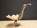 a bird that is standing on a table with a piece of paper in it ' s beak