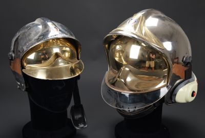 une paire de casques en argent et en or exposés sur un fond noir