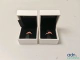 two white boxes with two rings inside of them on a table