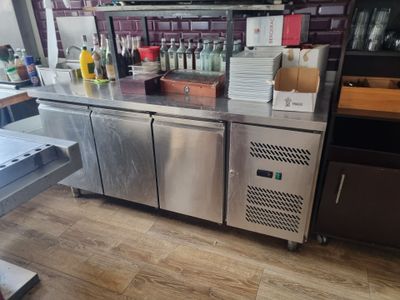 un comptoir en acier inoxydable dans un restaurant, sur lequel sont posées des bouteilles