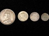 four different types of coins are shown on a black surface
