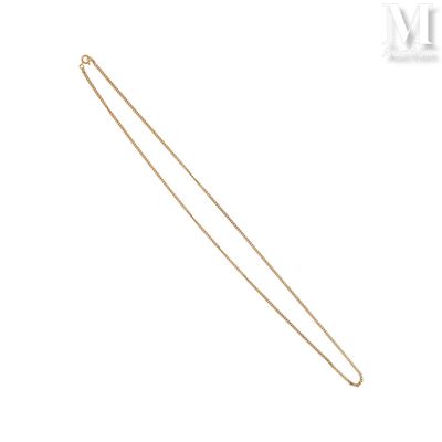 un gros plan d'un collier en or à longue chaîne sur fond blanc