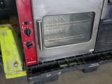 a silver oven sitting on top of a pallet in a warehouse