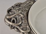 a silver plate with a dragon head on it next to a bowl