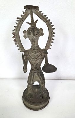 an old bronze statue of a man holding a bell in his hand