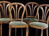 quatre chaises en bois, dotées de coussins rembourrés verts, sont disposées devant un fond noir