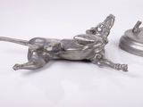 a silver dog figurine sitting next to a small metal object