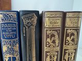 several old books are lined up on a shelf in a row