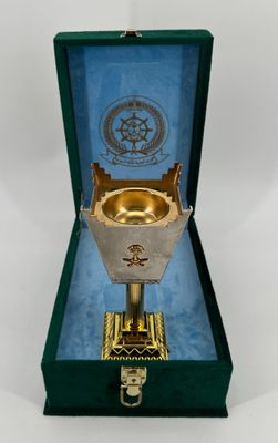 a gold chalicee in a green box on a white surface