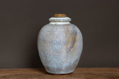 un vase bleu posé sur une table en bois, sur fond noir