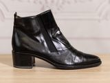 black leather ankle boots with zippers on a wooden table