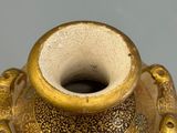 a gold vase sitting on a table with a gray background