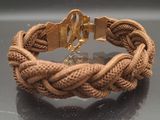 braided bracelet with a gold clasp on a black surface