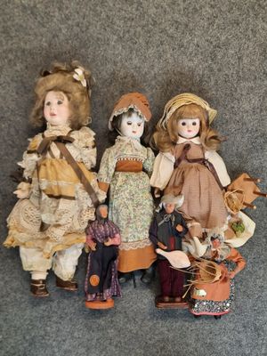 three antique dolls are lined up on a gray surface