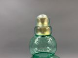 a green glass bottle with a gold top